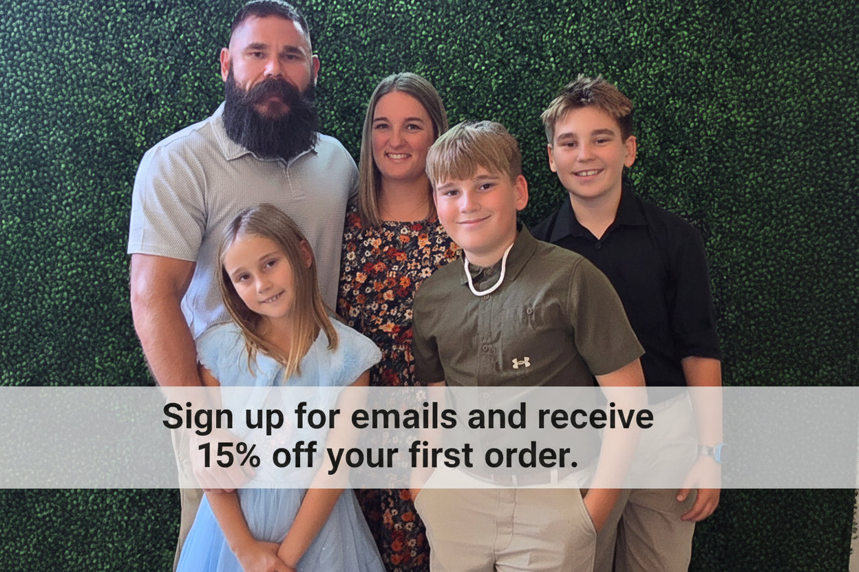 Family of five posing together in front of a green hedge